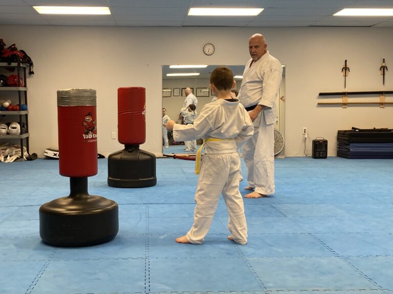 Image of Charlestown, Indiana Shotokan Karate Sensei training a yellow belt student on a punching bag.