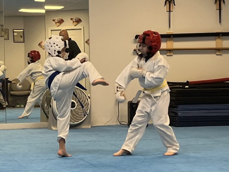 Image of Charlestown, Indiana Shotokan Karate Sensei watching one of his students practice kicks with a classmate.