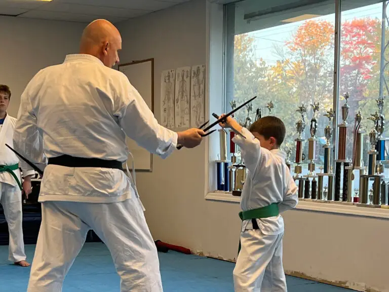 Image of Charlestown, Indiana Shotokan Karate Sensei training Sai weapons with student. The student is a green belt.
